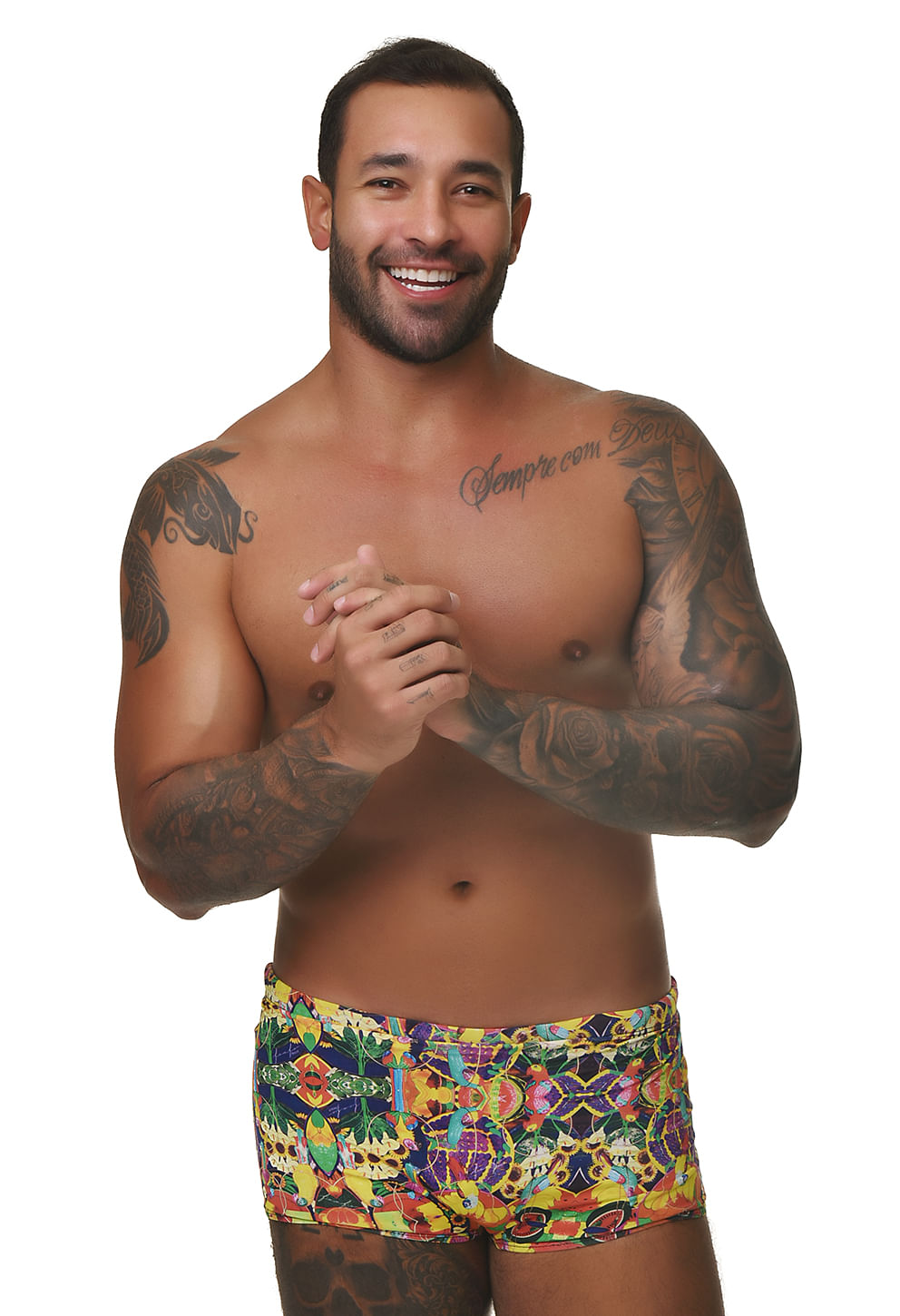 Homem adulto em estúdio com fundo branco vestindo sunga short de modelagem boxer curta com estampa tropical multicolorida.