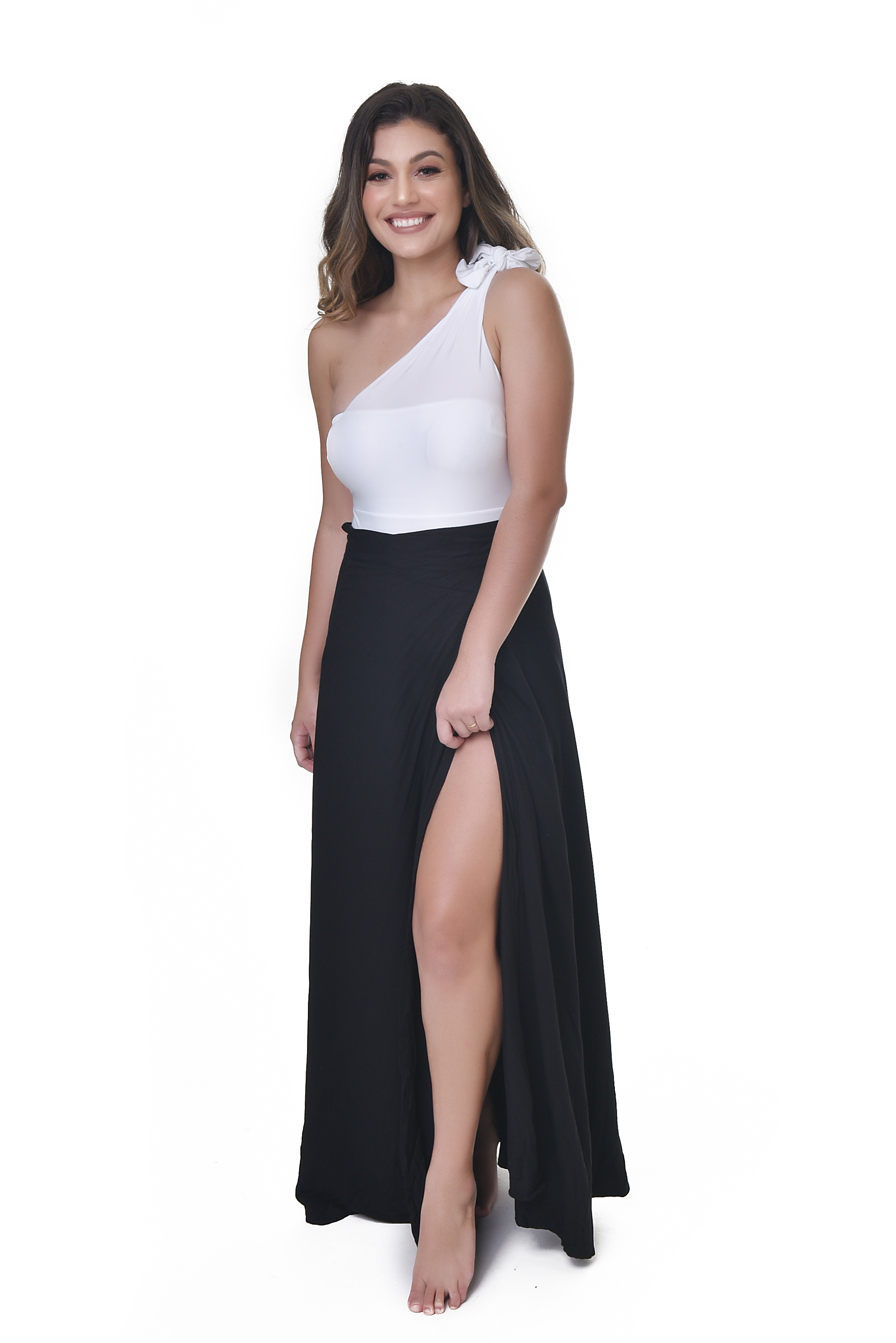 Modelo sorridente usando saia longa preta transpassada com fenda alta e body branco