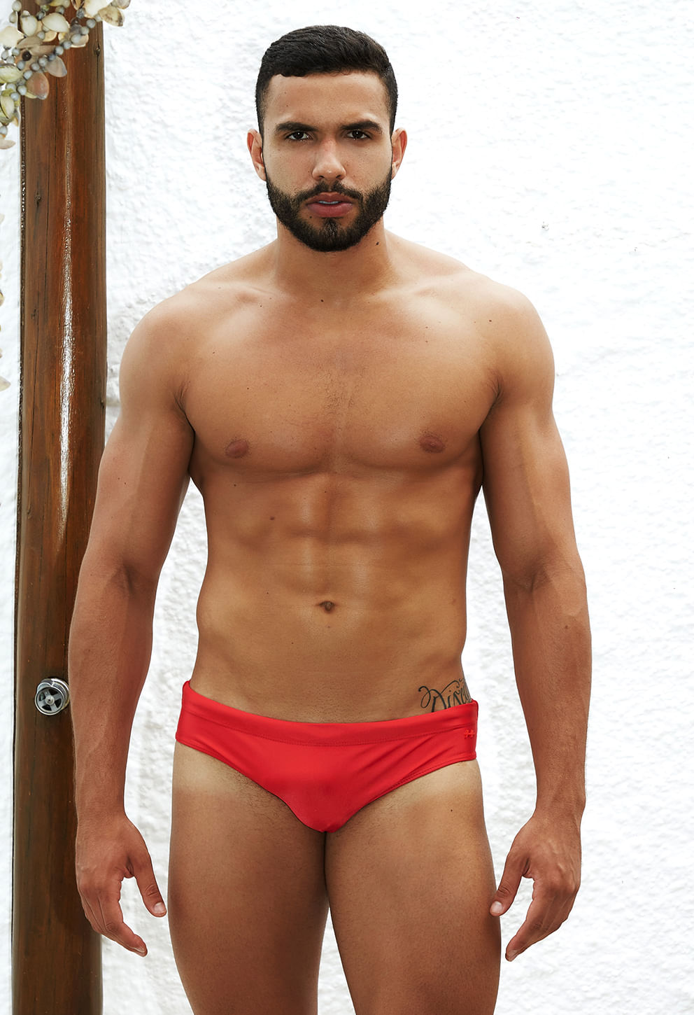 Vista frontal de um homem adulto usando uma sunga slip na cor carmim vibrante