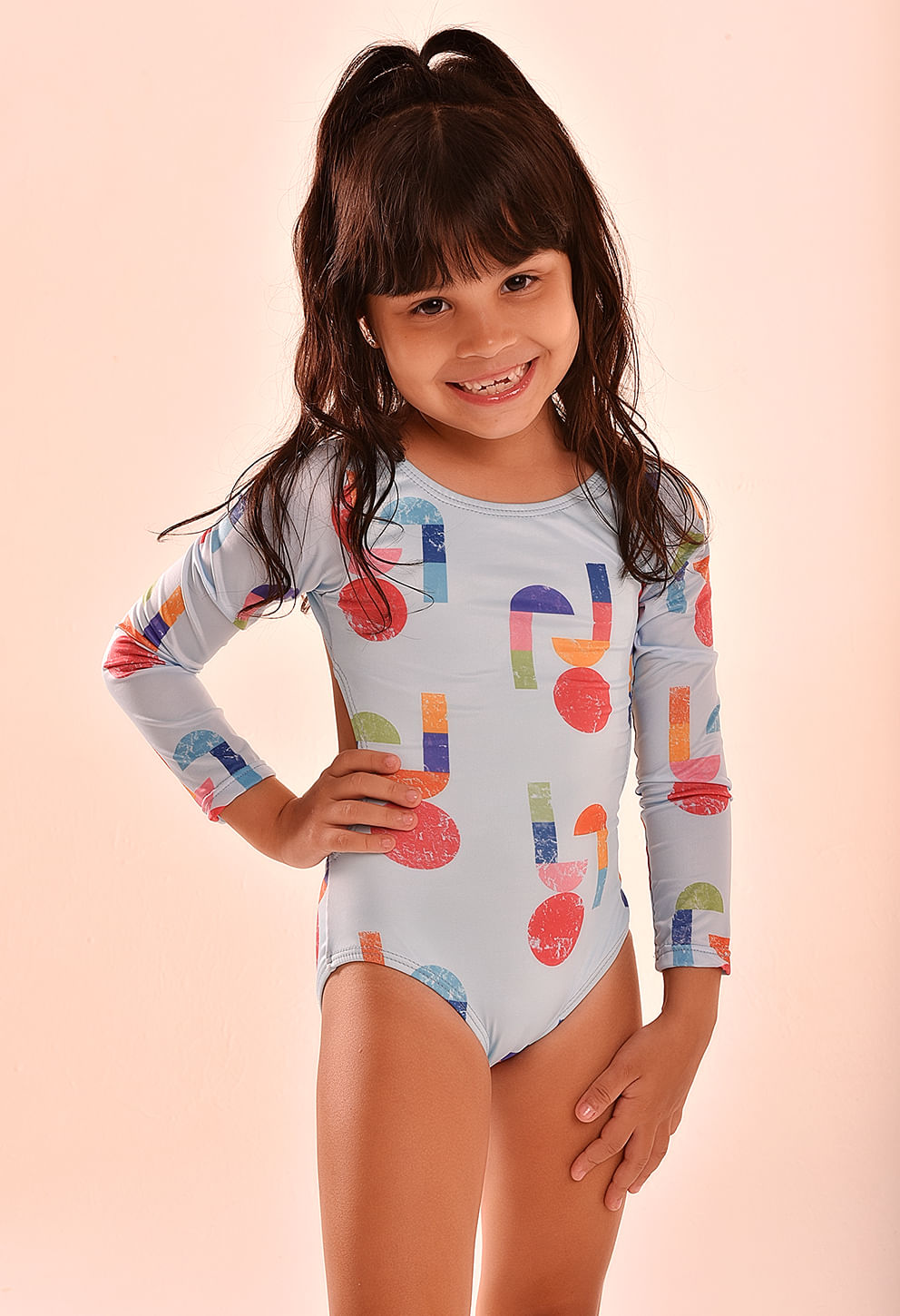 Menina sorridente vestindo maiô de manga longa estilo Pac Man em azul claro