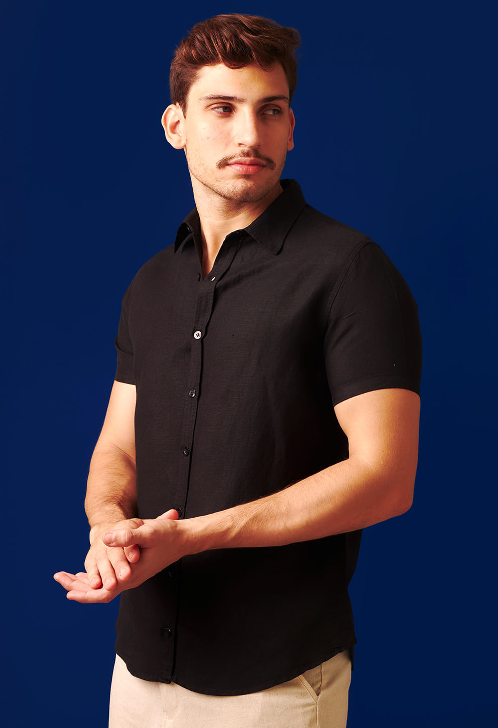 Visão lateral de modelo com camisa preta de manga curta em tecido leve