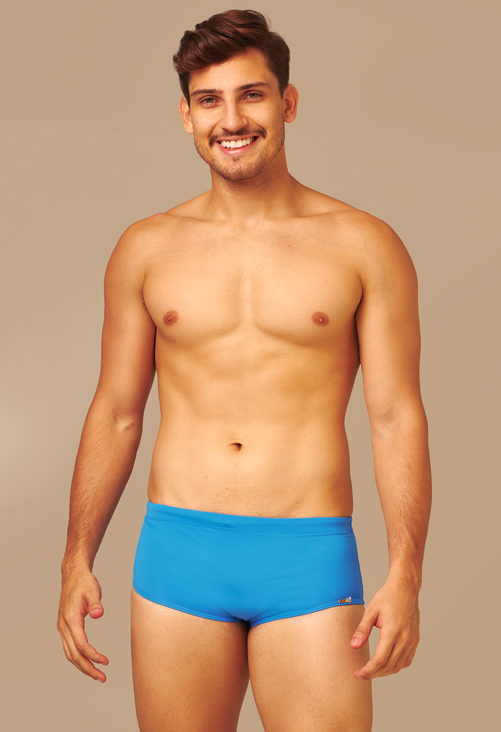 Frontal: homem usando sunga short azul vibrante, detalhe metálico dourado