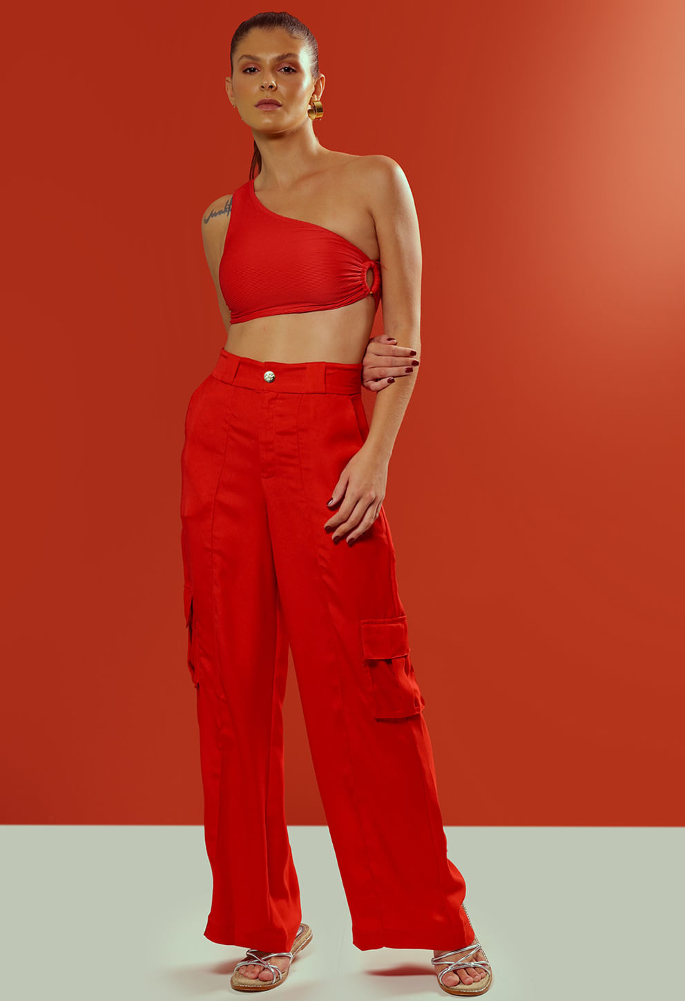 Modelo em pé com calça pantalona vermelha Maçã Do Amor, bolsos laterais cargo e botão dourado
