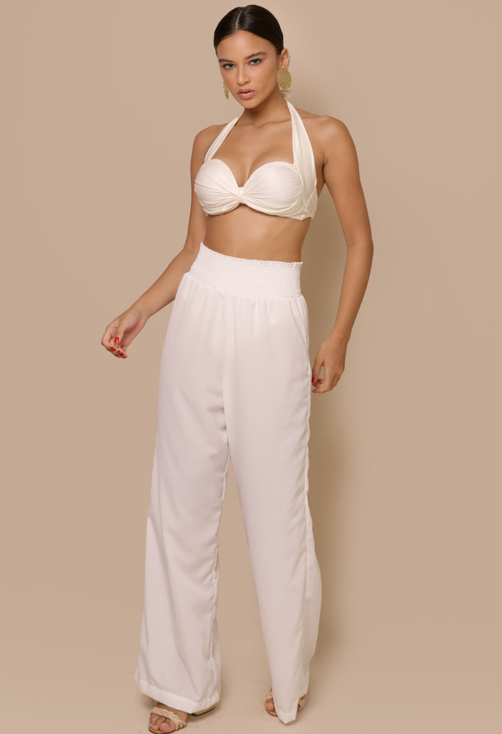 Imagem frontal de modelo usando calça pantalona Donatella Off White com cós largo e tecido fluido