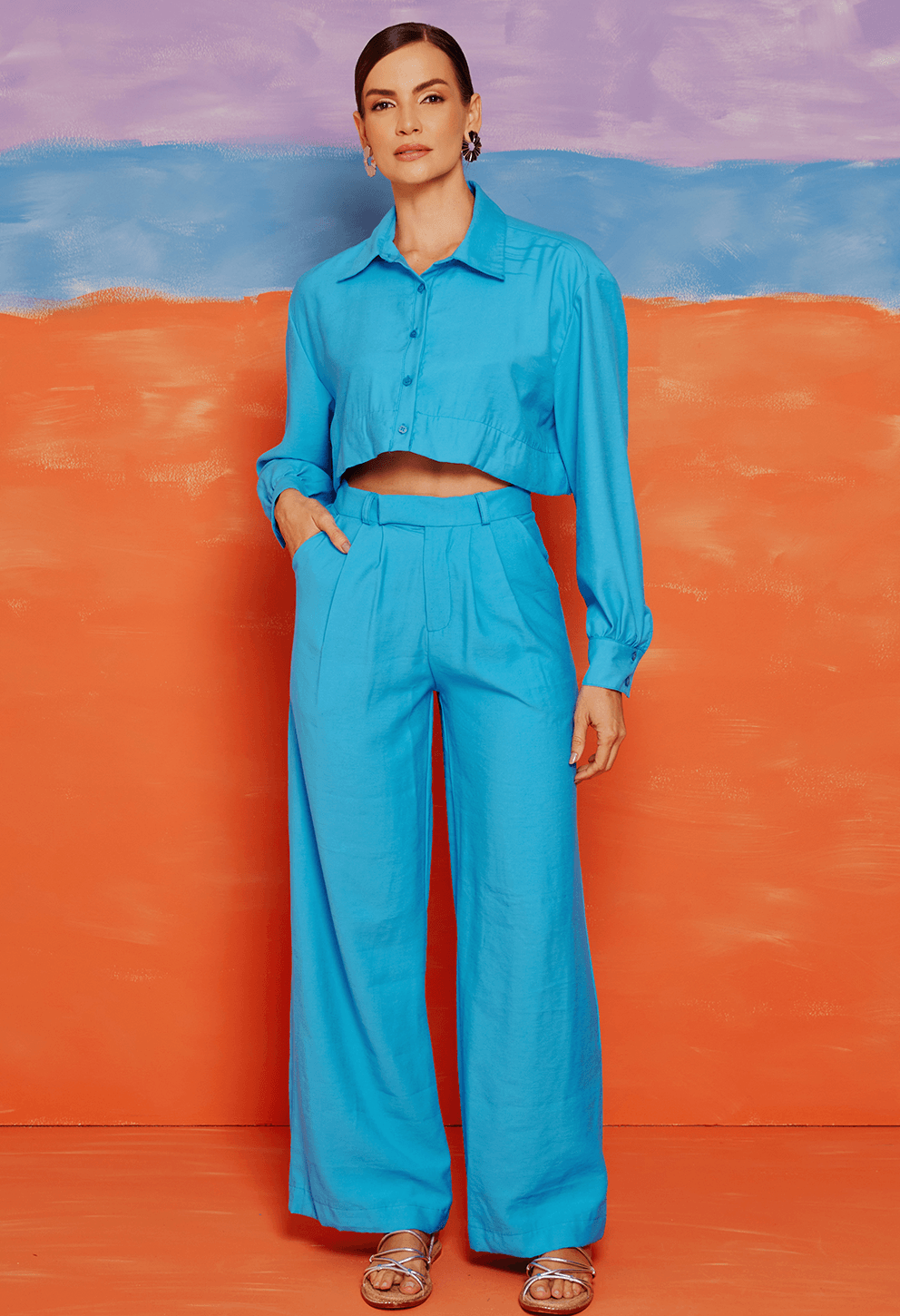 Modelo usando calça pantalona azul crepúsculo com cintura alta, pregas frontais e bolsos laterais