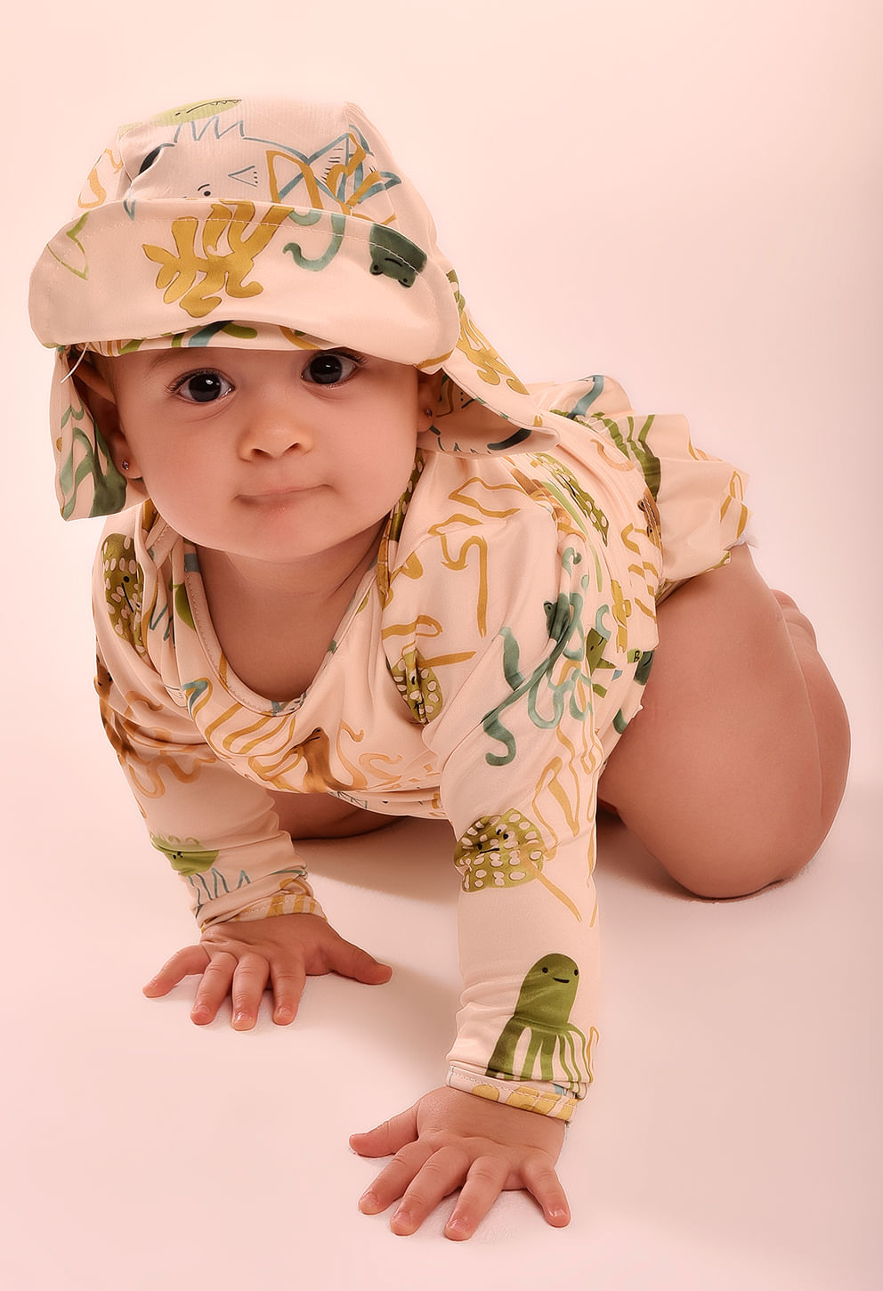 Bebê engatinhando com camisa manga longa e chapéu combinando, estampa marinha