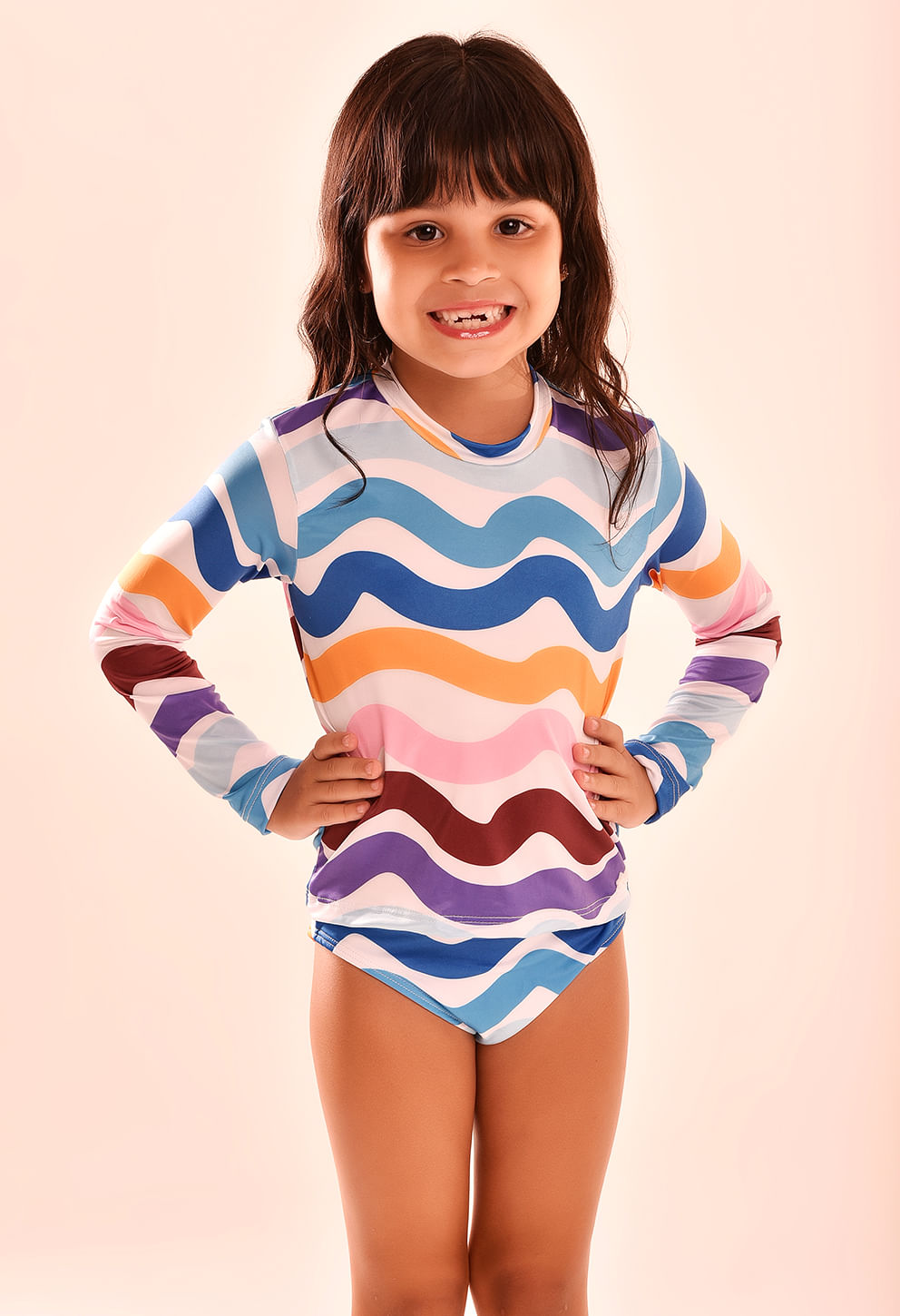 Criança usando camisa manga longa infantil estampa ondulada multicolor em fundo rosado