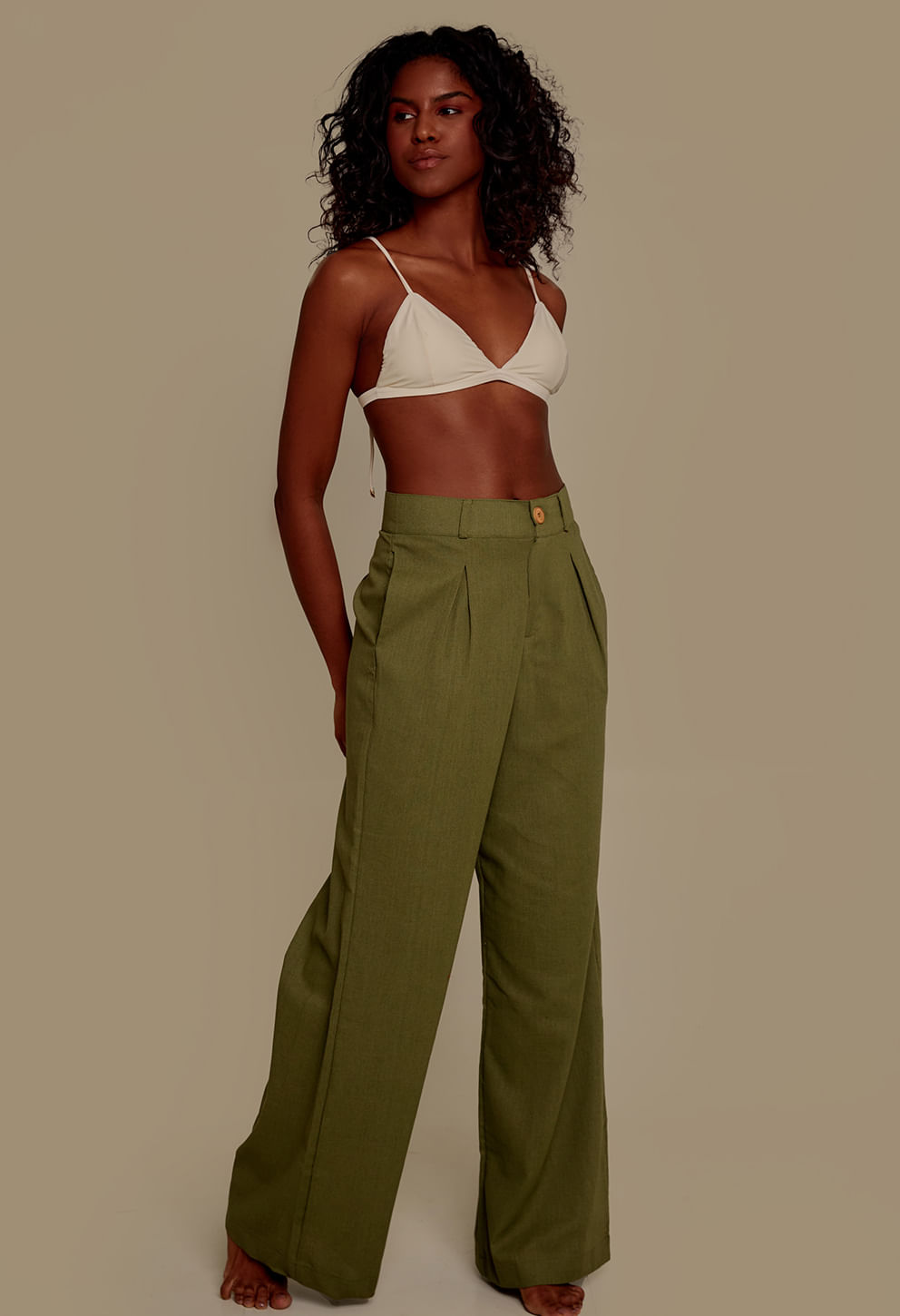 Calça pantalona social verde folha de bananeira vista de lado, destacando o caimento amplo e os bolsos laterais.