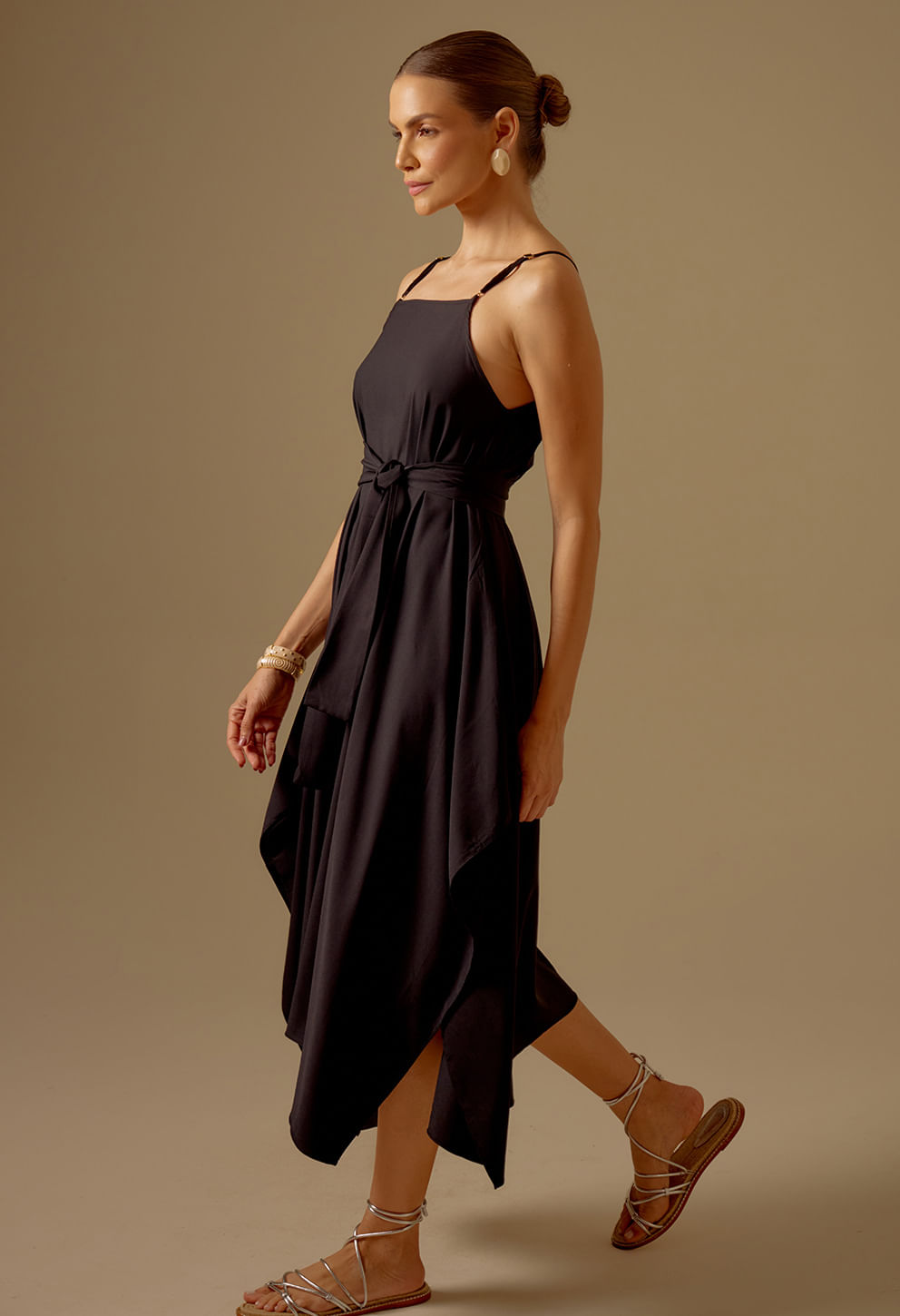 Perfil da modelo usando Vestido Angélica Preto com faixa na cintura e barra assimétrica