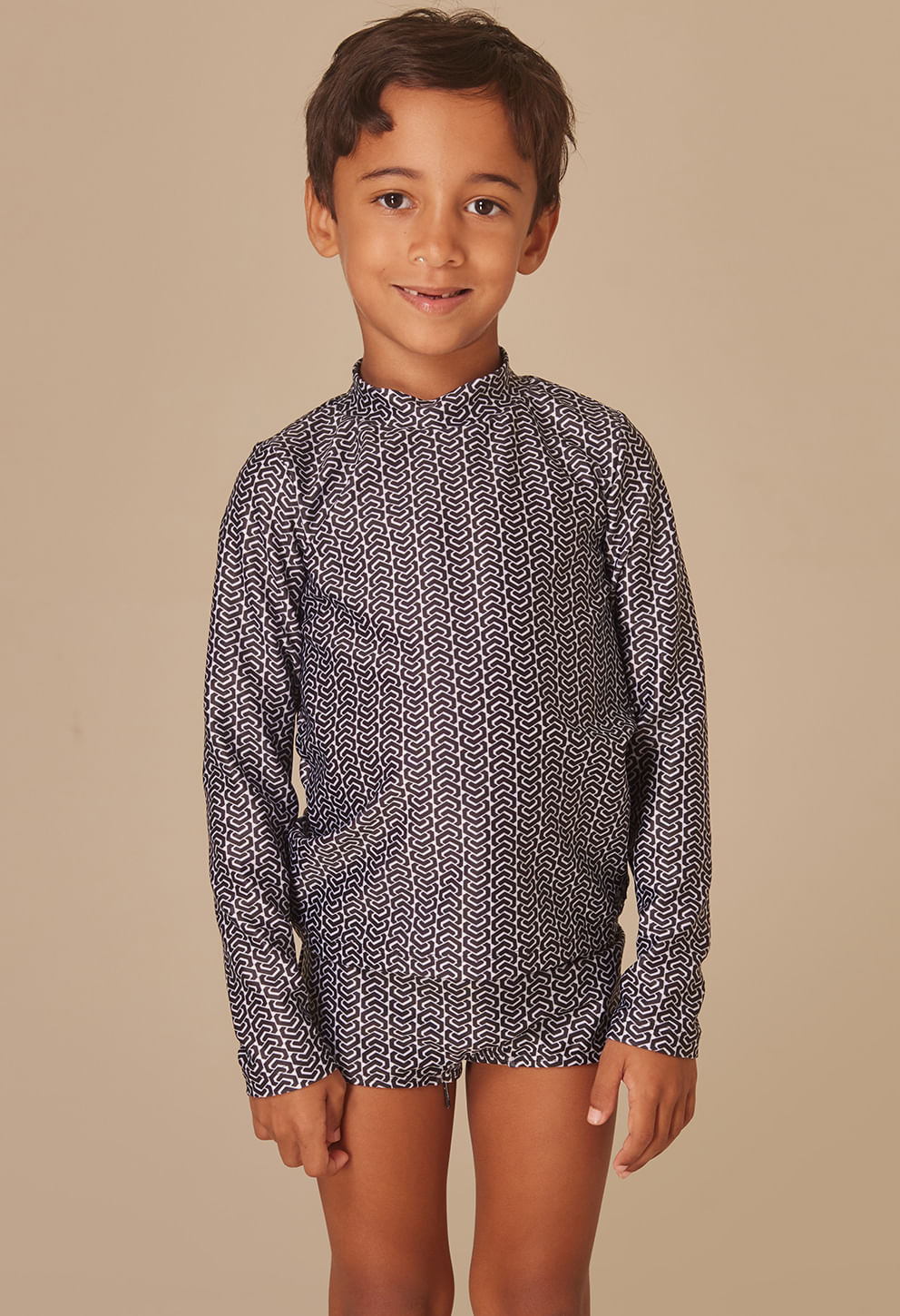 Menino com sunga short infantil abstrata preto e branco, vista frontal, fundo bege