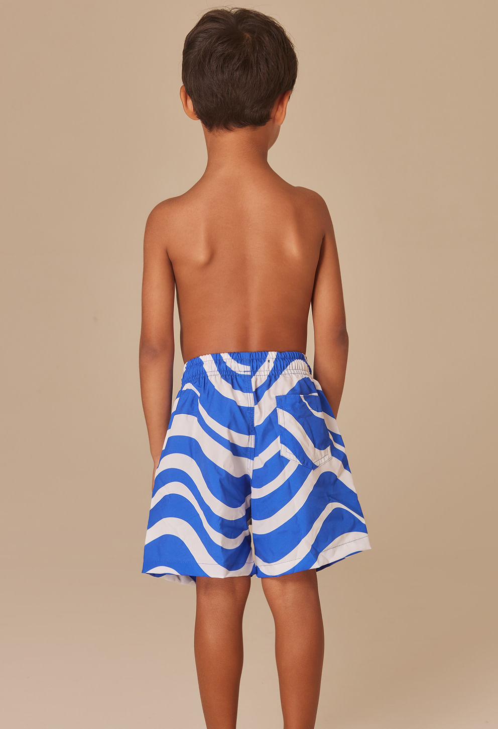 Imagem traseira de menino usando bermuda infantil azul e branca com estampa ondulada
