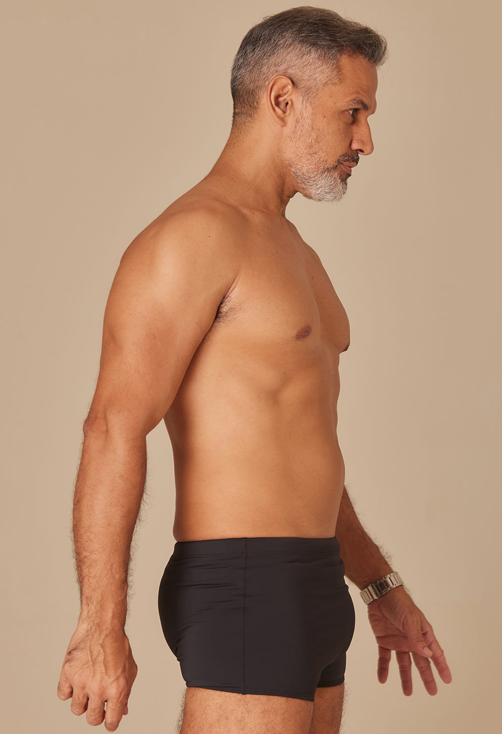 Imagem lateral de homem adulto usando sunga short preta lisa