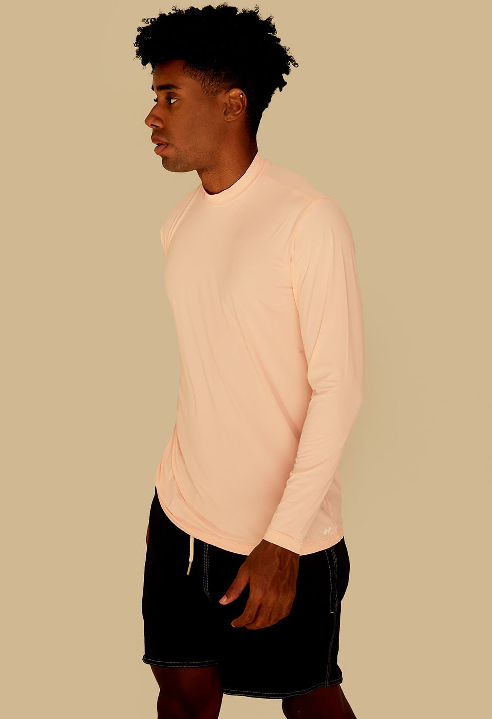 Visão lateral da camisa UV pêssego/rosa claro, mostrando caimento e acabamento