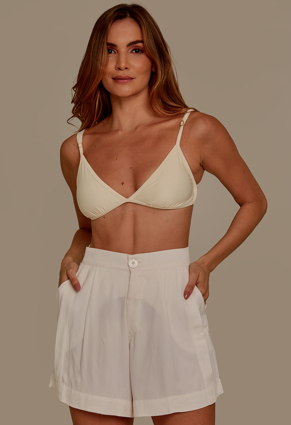 Modelo feminina usando short branco de tecido leve e fluido, cintura alta, bolso lateral e barra dobrada
