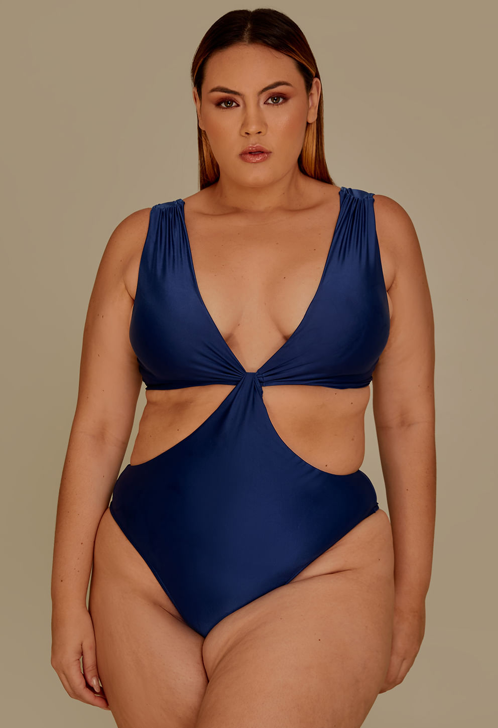 Modelo plus size usando body azul marinho com recortes laterais e nó frontal, destaque para o design e cor
