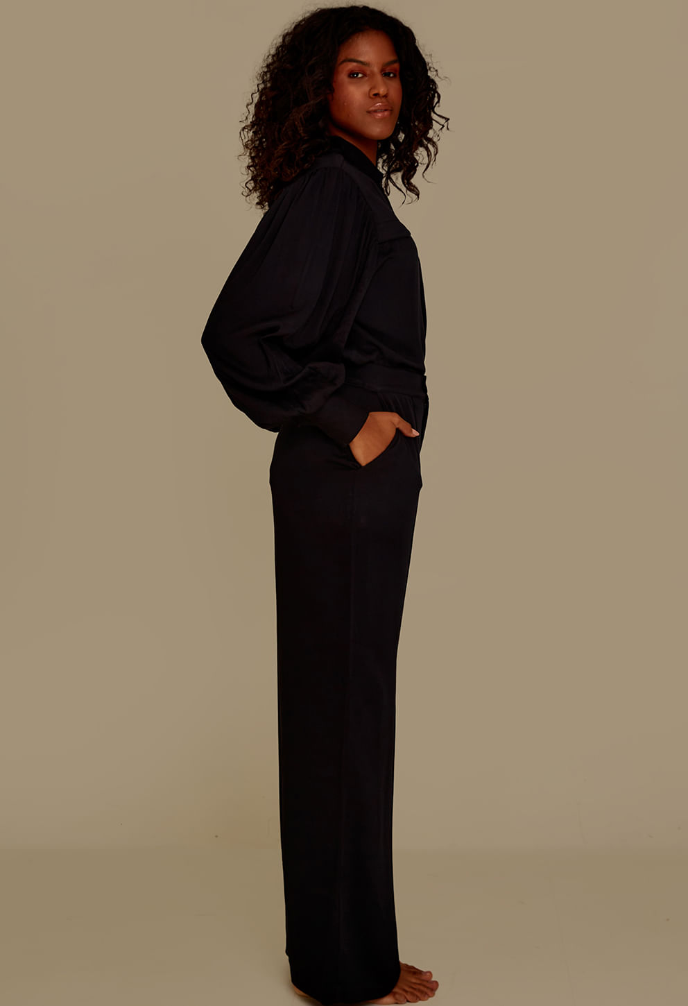 Visão lateral da calça pantalona preta mostrando o corte largo e o bolso