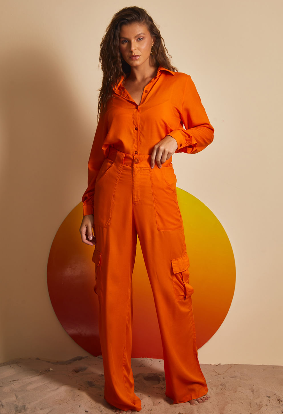Mulher usando calça pantalona laranja vibrante de cintura alta com bolsos frontais e laterais