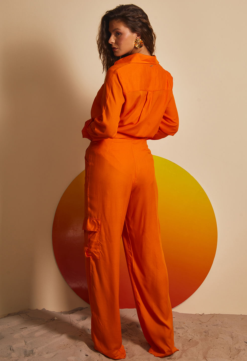 Vista traseira da calça pantalona laranja com bolso lateral abotoado