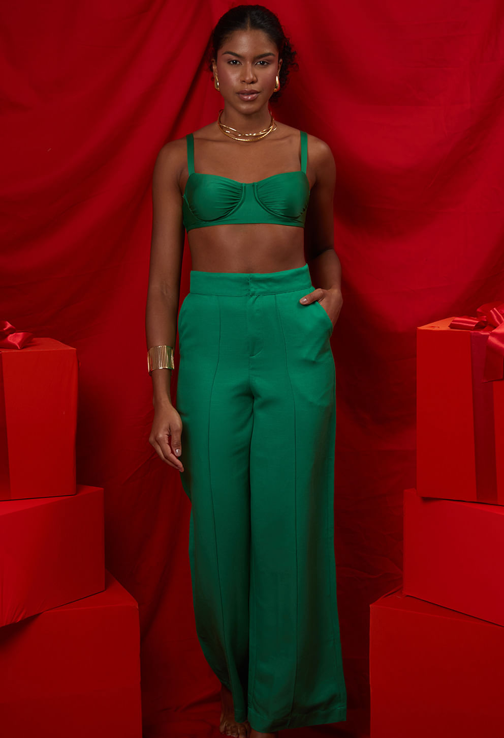 Modelo usando calça pantalona verde esmeralda de cintura alta com top combinado e acessórios dourados