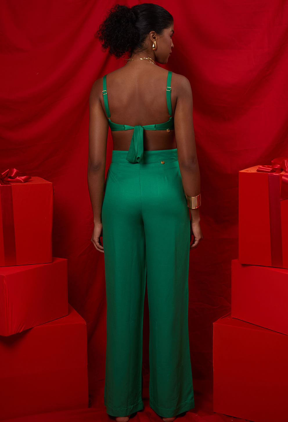 Vista de costas da calça pantalona verde esmeralda mostrando caimento e detalhe dourado na cintura