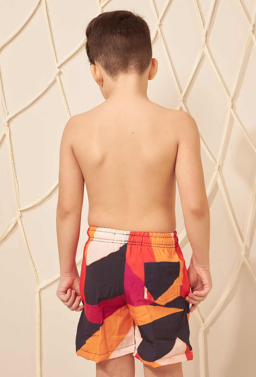 Menino de costas usando bermuda infantil estampada vibrante com cós elástico e bolso traseiro