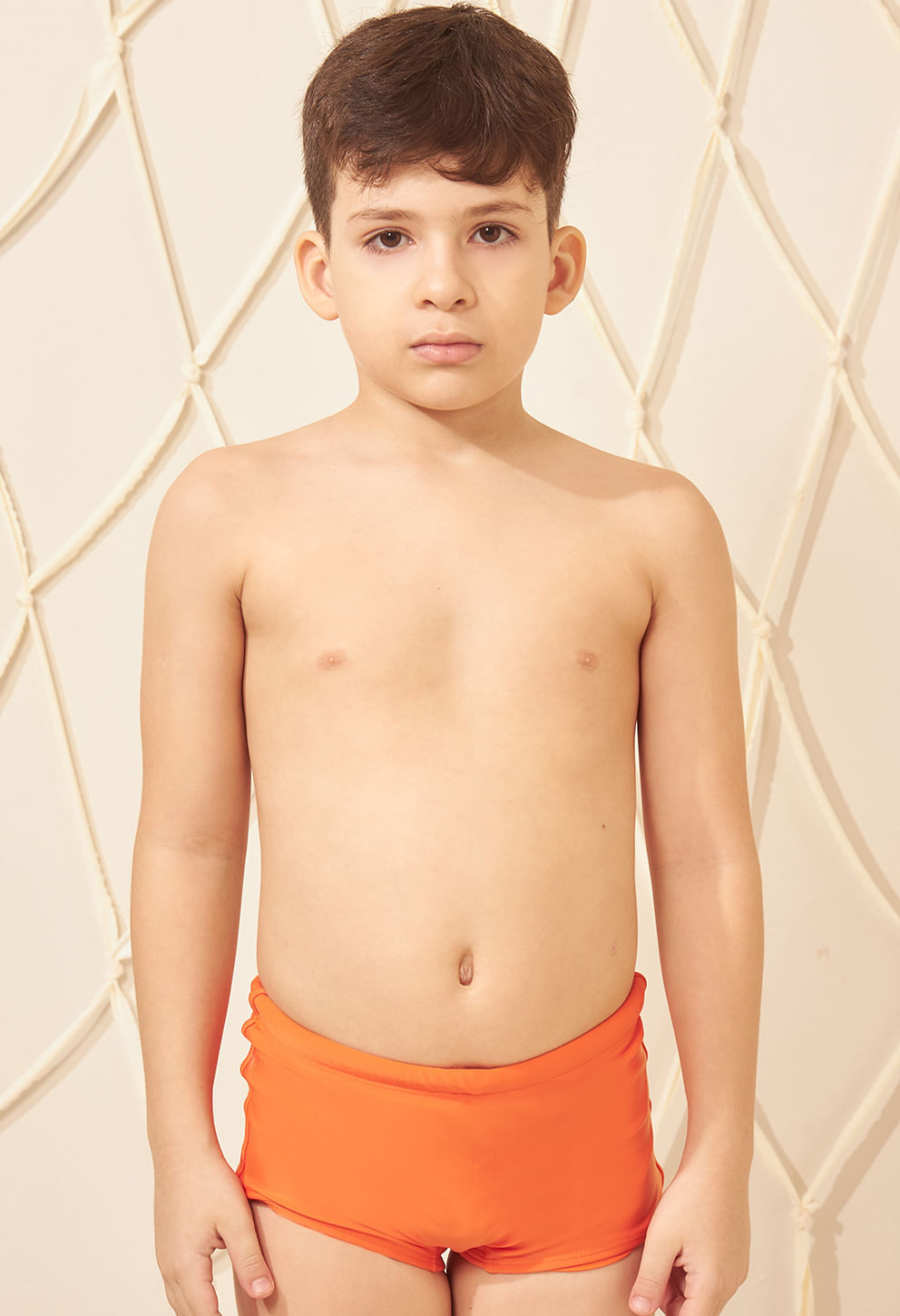 Sunga short infantil laranja vibrante vista de frente em fundo bege