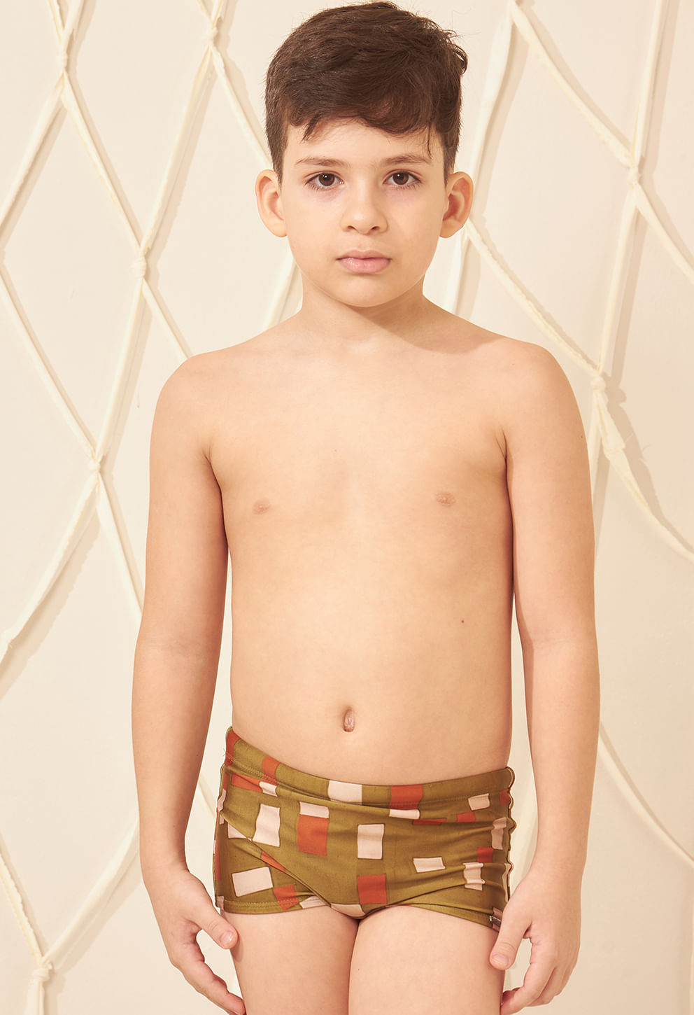 Criança usando sunga short infantil estampada em verde musgo, laranja e bege, vista frontal