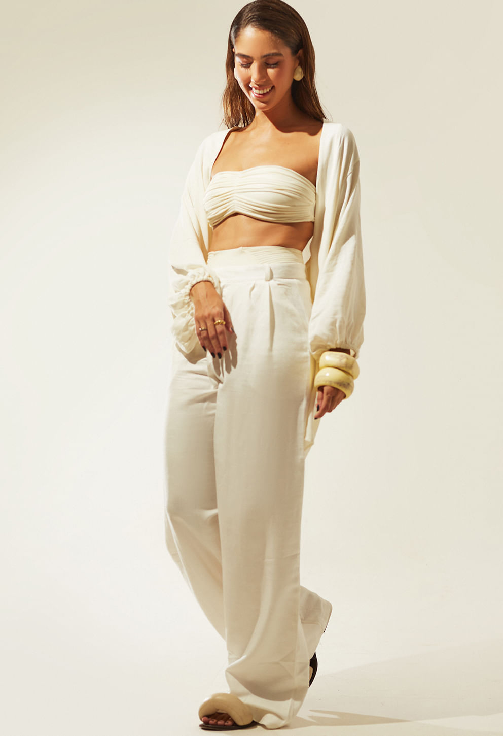 Modelo usando calça pantalona off white com top e casaco leve, look casual chic