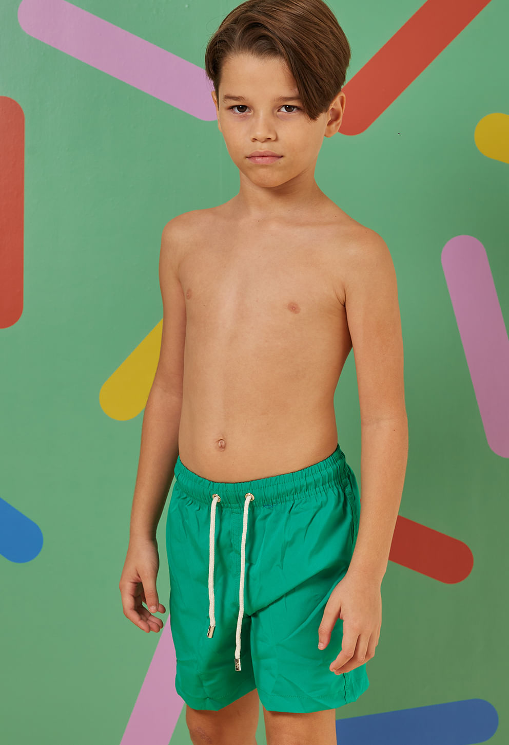 Menino vestindo bermuda infantil verde jóia com elástico e cordão branco, bolsos laterais