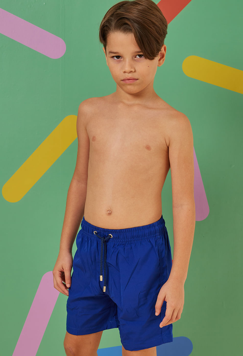 Menino posando de frente vestindo bermuda praia infantil azul bic com cós elástico e cordão regulador