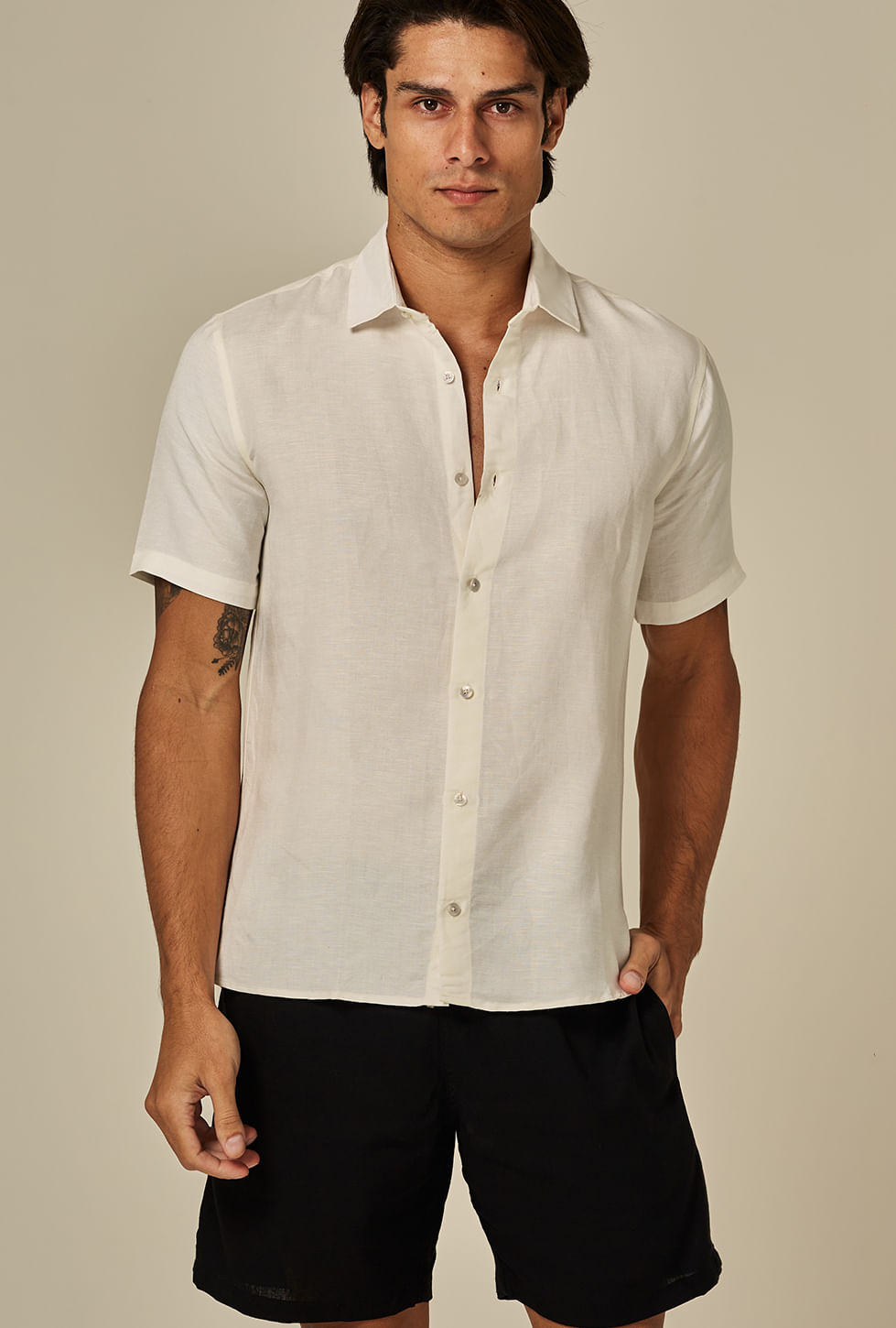 Modelo masculino usando bermuda casual shortinho preta, frontal, fundo bege
