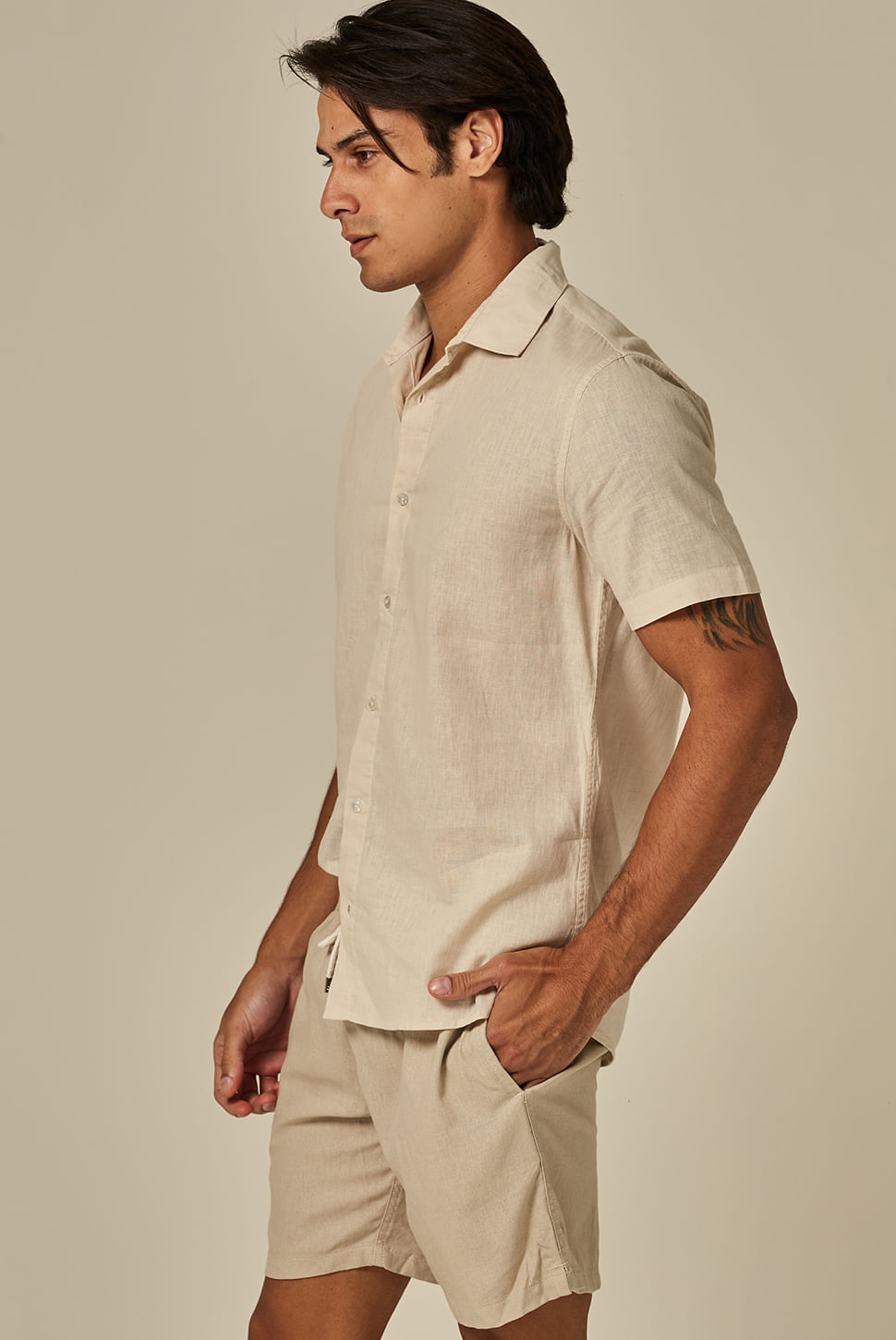 Perfil com bermuda casual bege claro de linho, cordão ajustável e bolso lateral, em fundo neutro