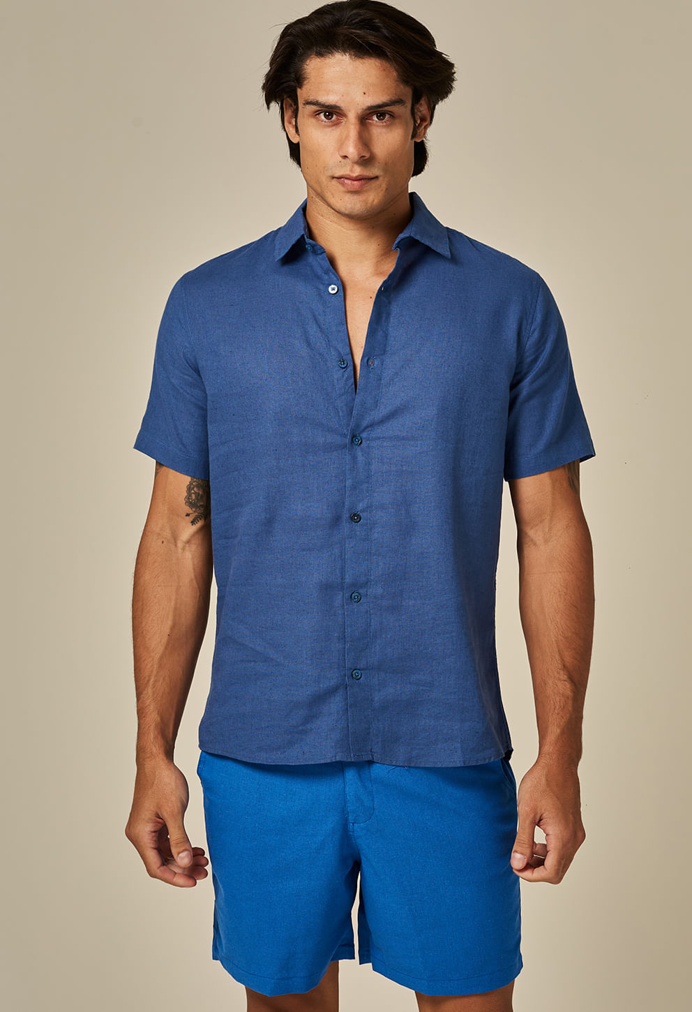 Modelo masculino vestindo camisa de linho slim manga curta cor índigo, frente, fundo bege