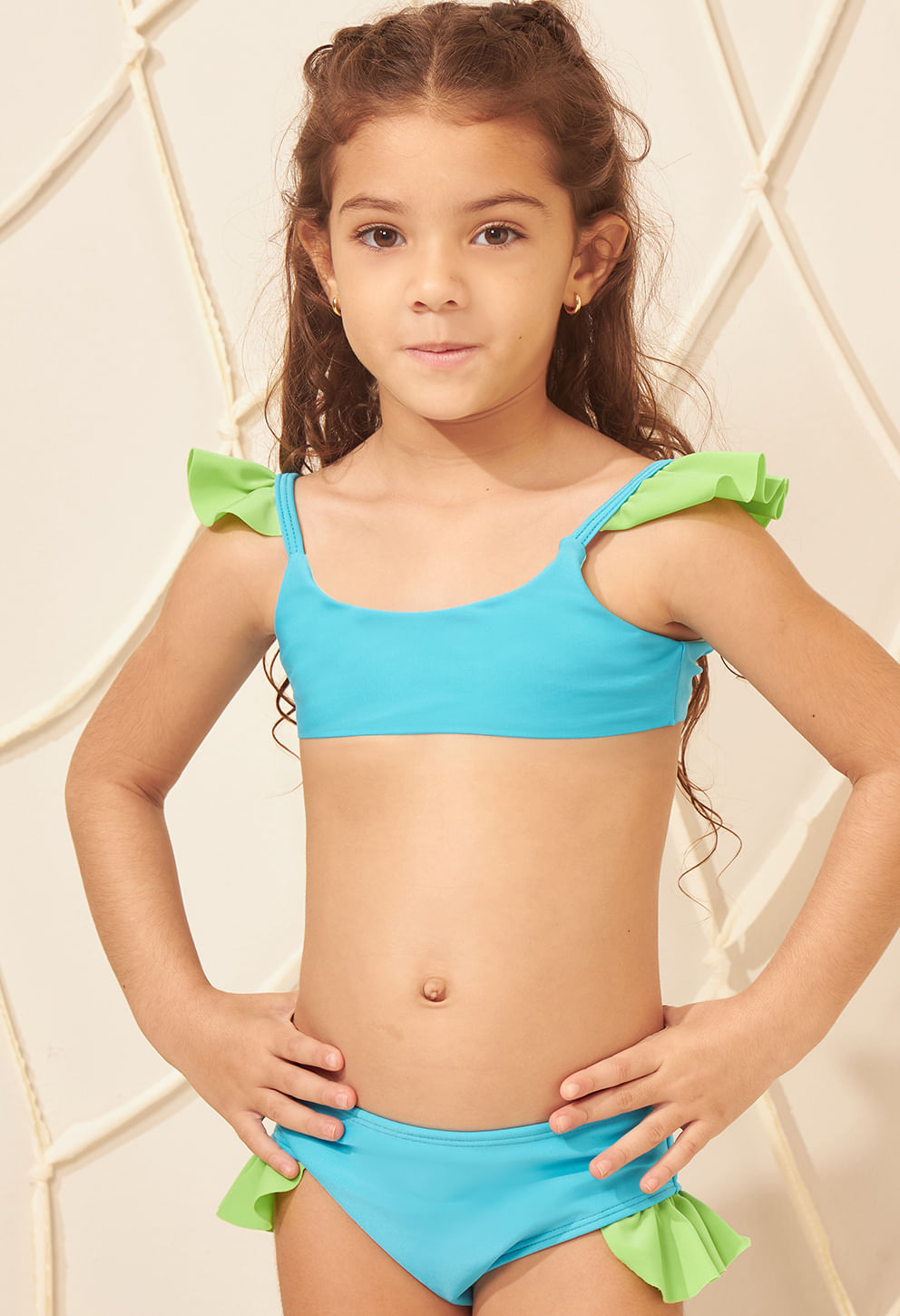 Menina usando biquíni azul com detalhes verdes e babados, vista frontal