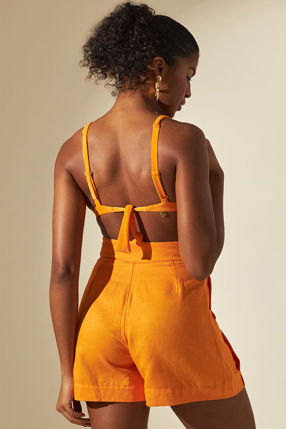 Modelo de costas usando Short Milão Siri laranja com pregas e bolsos