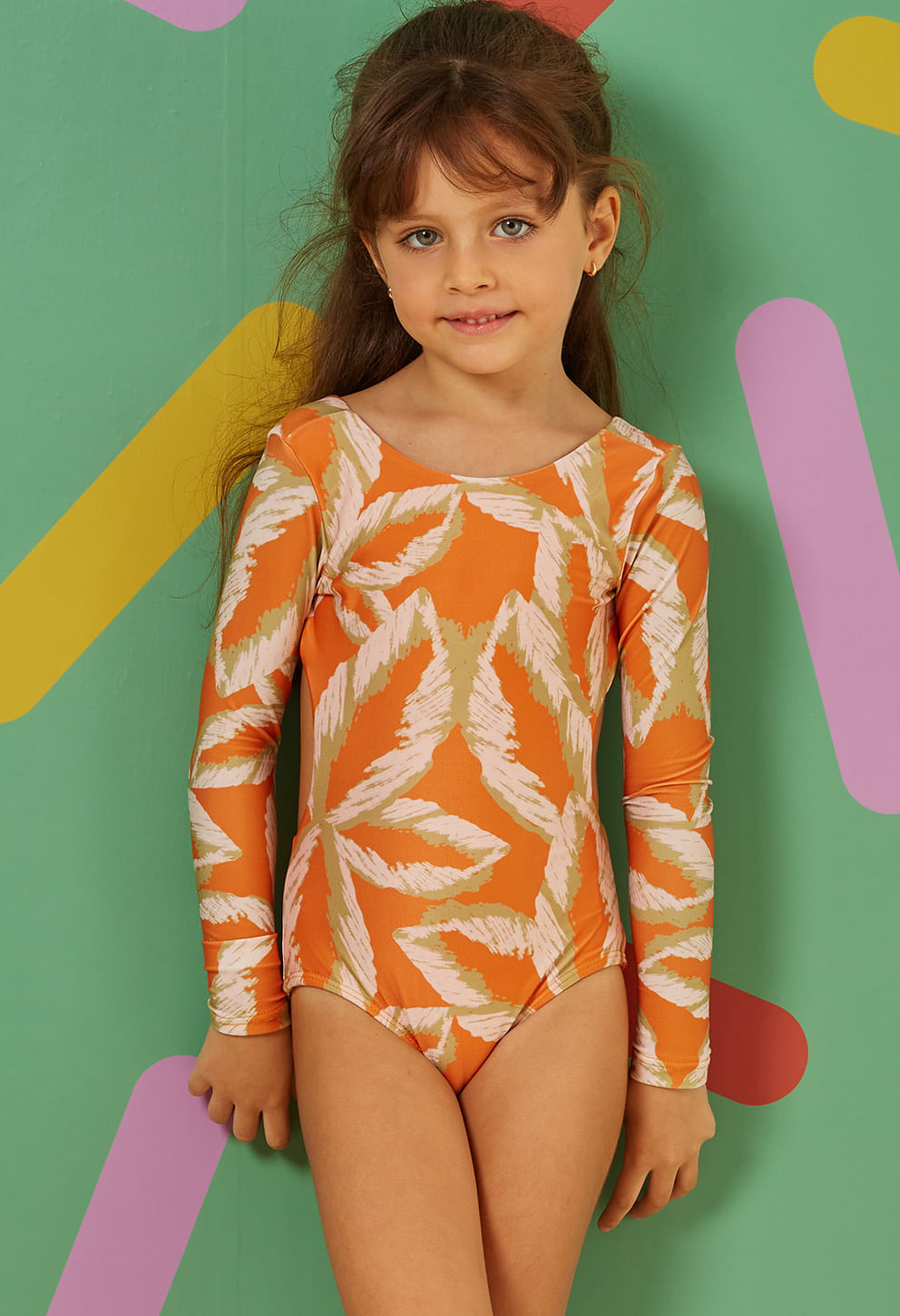 Menina vestindo maiô engana mamãe laranja com estampa de folhas, mangas longas e laço nas costas.