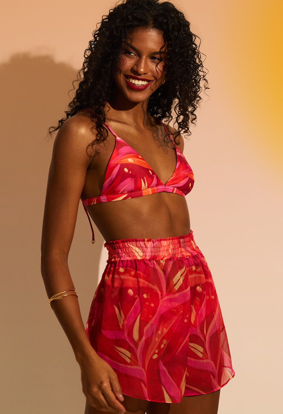 Modelo usando short rosa vibrante vista lateral, sorriso e combinação com top