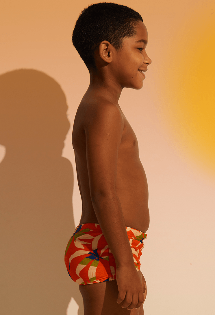 Foto lateral mostrando caimento da sunga short infantil laranja com estampa