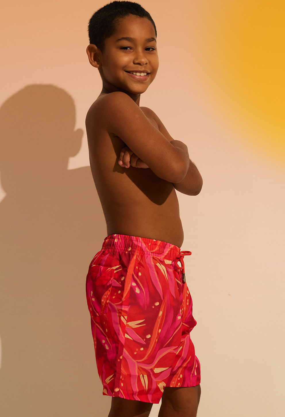 Menino de perfil usando bermuda infantil rosa com bolsos e cordão