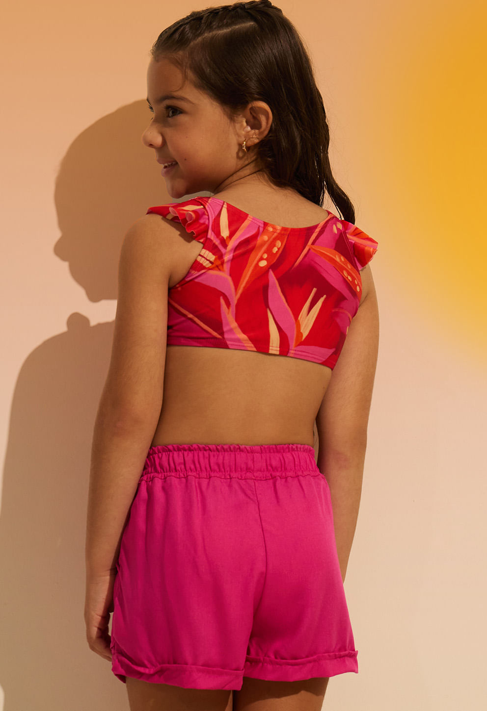 Modelo de costas mostrando cós elástico e bainha dobrada do short rosa pink