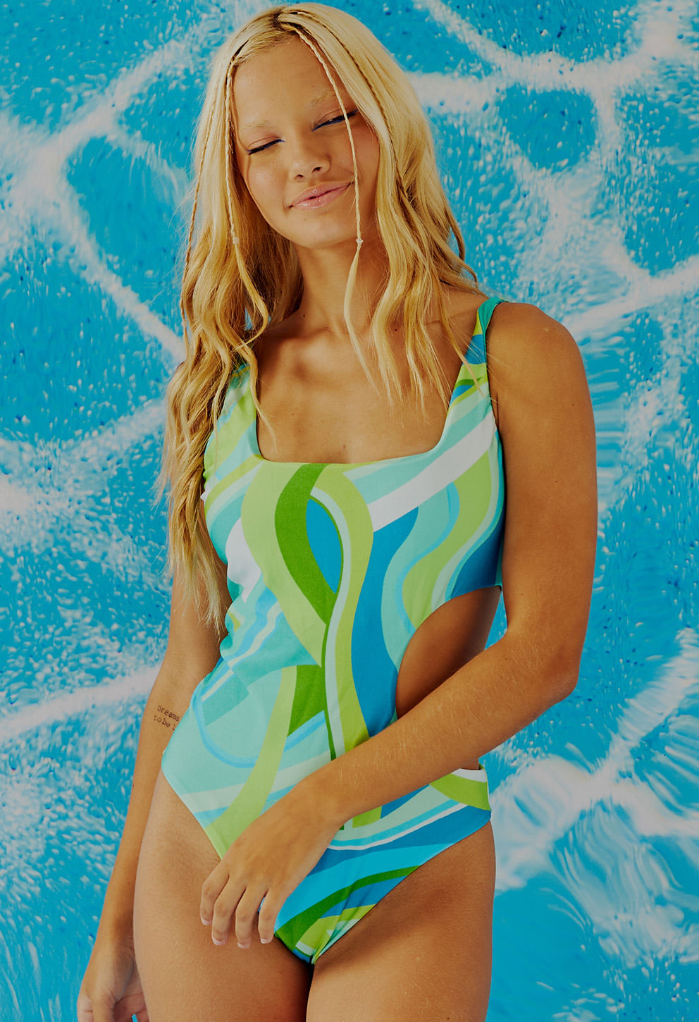 Modelo vestindo Body Kanandra Ondas estampado em azul, verde e branco com recorte lateral