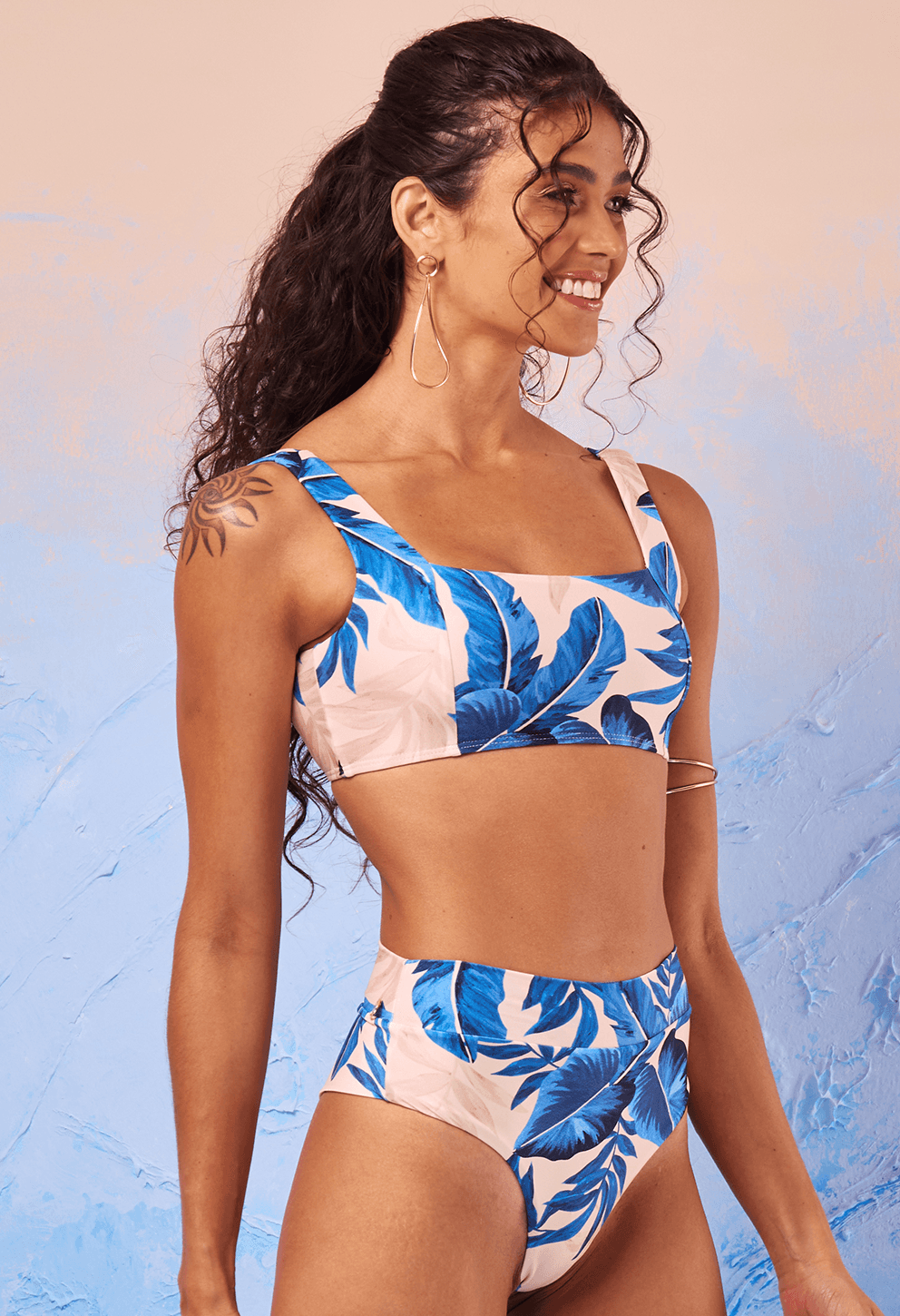 Modelo vista de lado sorrindo usando o Top Sophia Terra Azul com estampa de folhas