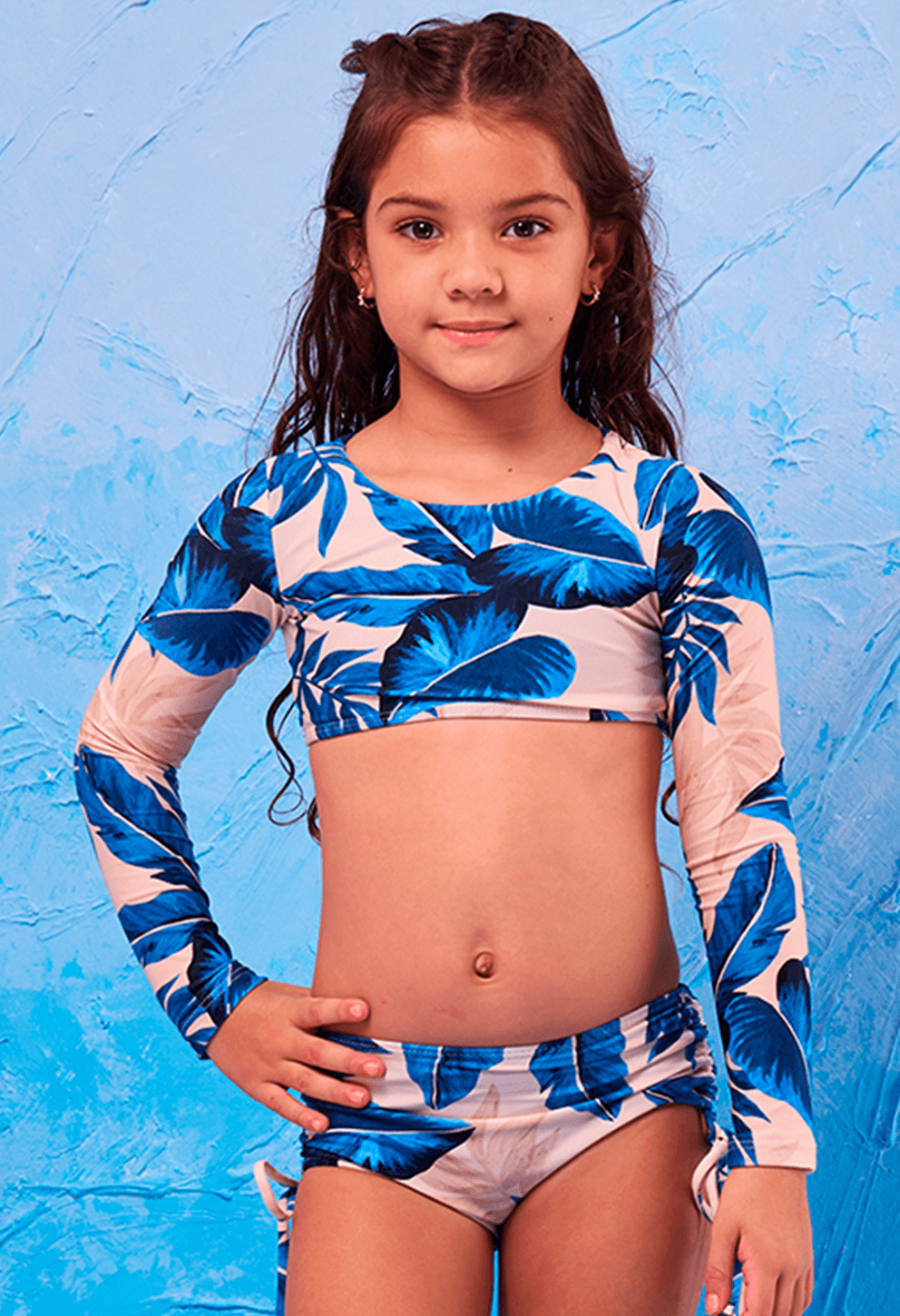 Menina criança posando de frente, vestindo biquíni Valentina Terra Azul com estampa de folhas azuis e bege