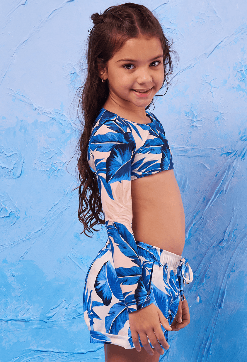 Imagem lateral de menina usando short infantil com cordão na cintura e blusa cropped