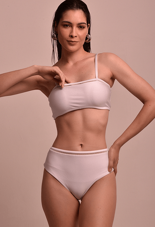 Modelo frontal usando top reto branco com entremeio decorativo na barra superior, alças finas e cós alto da parte de baixo visível
