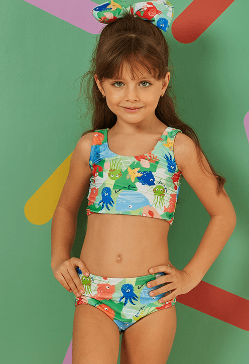 Menina infantil usando biquíni duas peças com estampa marítima colorida em verde claro.