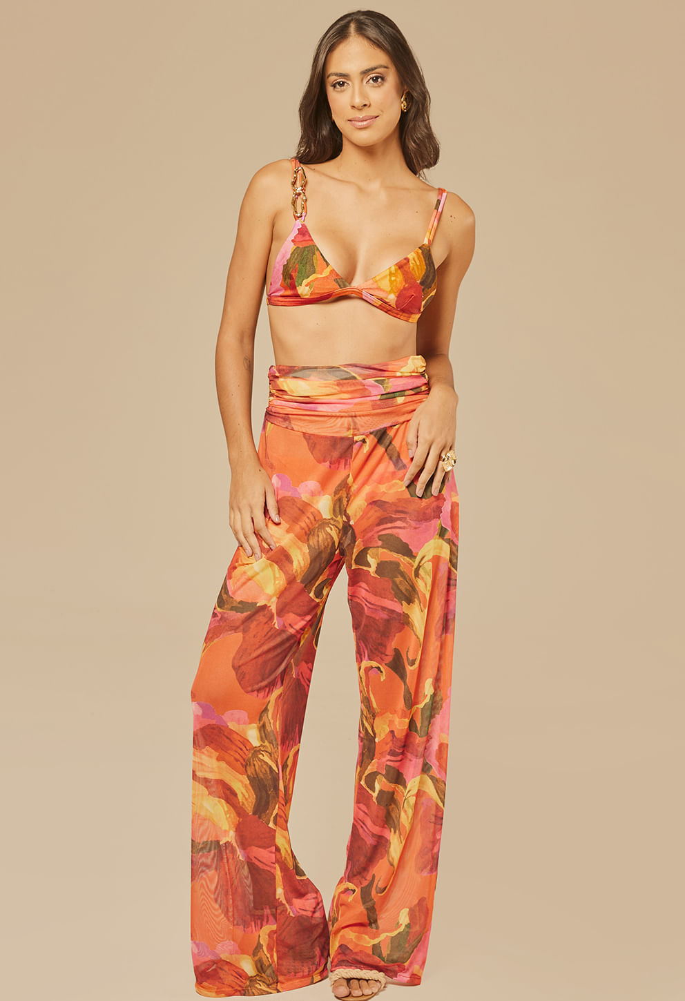 Calça Pantalona Norma Chamego frontal, estampa vibrante em tons de laranja, vermelho, rosa, amarelo e verde