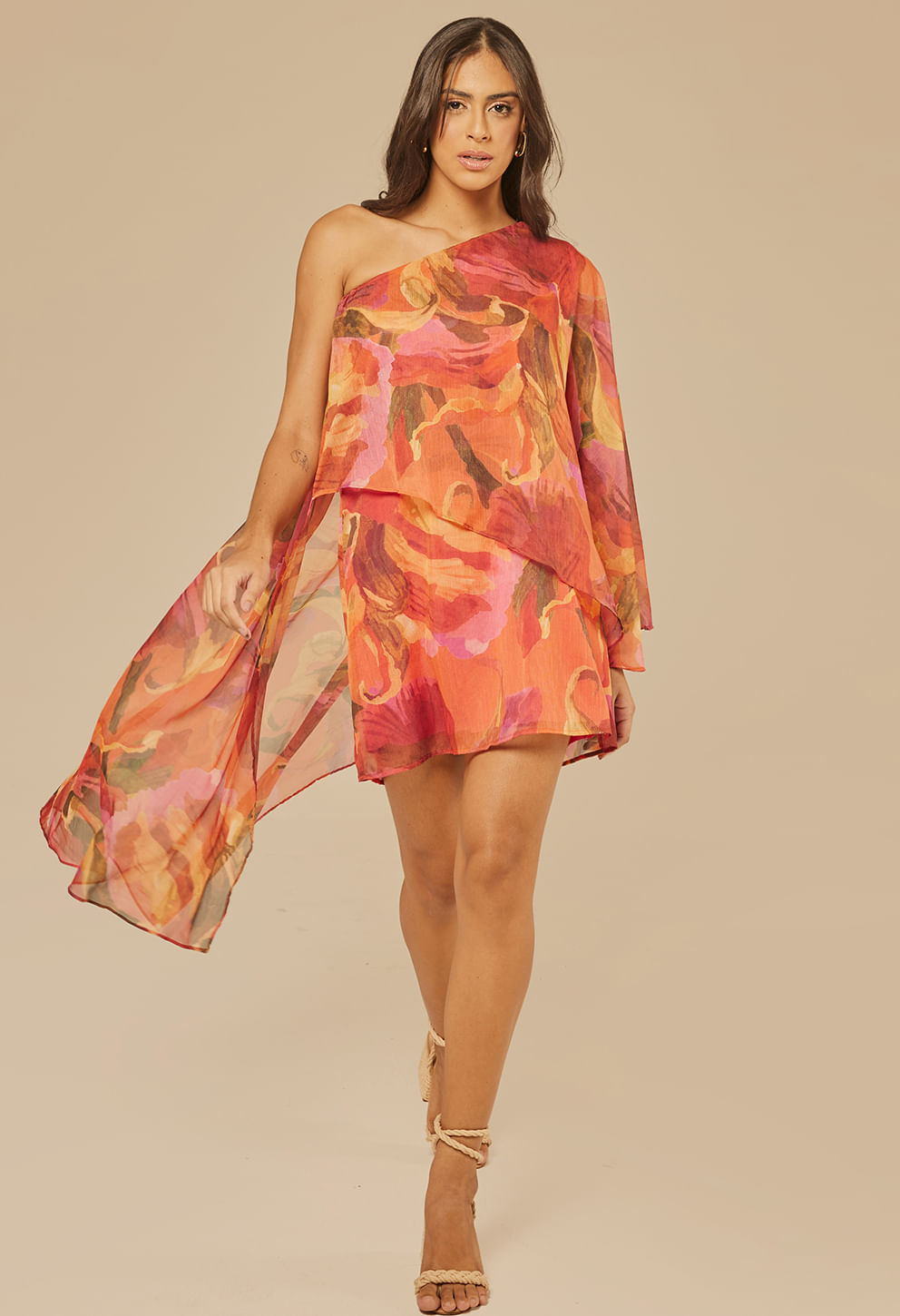 Modelo usando Vestido Cibele Chamego, curto assimétrico com estampa floral em tons de laranja, vermelho e rosa