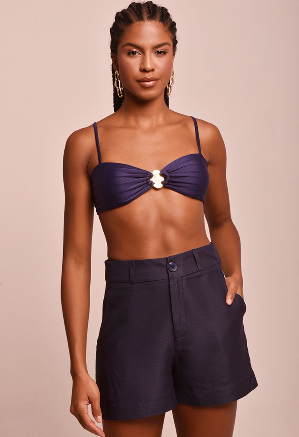 Short azul marinho alfaiataria com bolsos laterais e botão frontal, combinado com top azul marinho, modelo em fundo bege