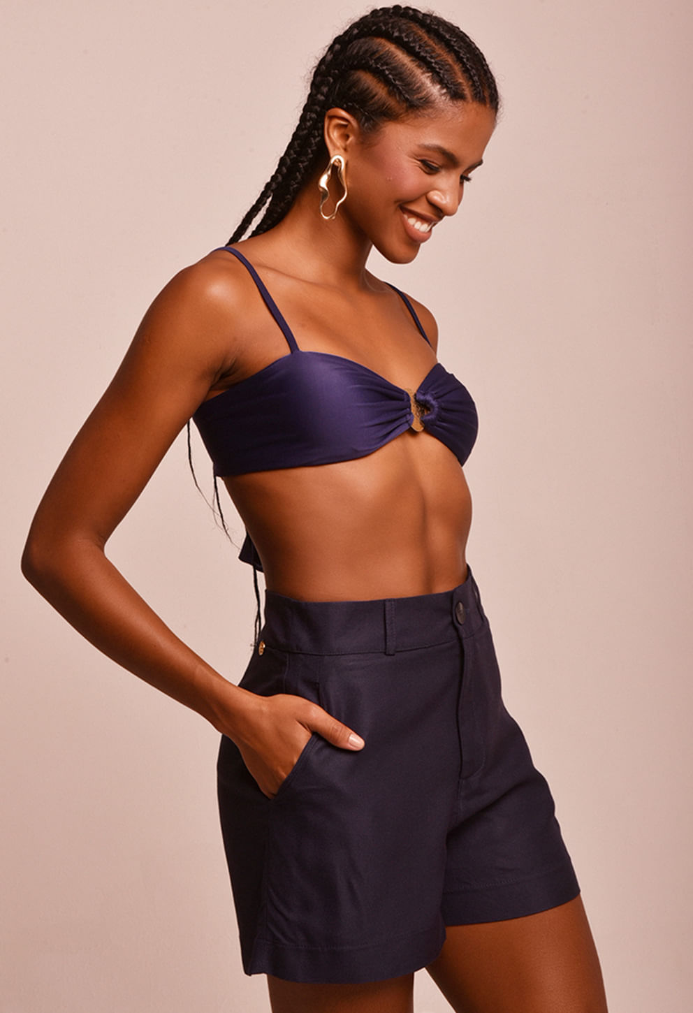 Modelo usando short azul marinho de alfaiataria visto de perfil, destacando o caimento e bolsos laterais